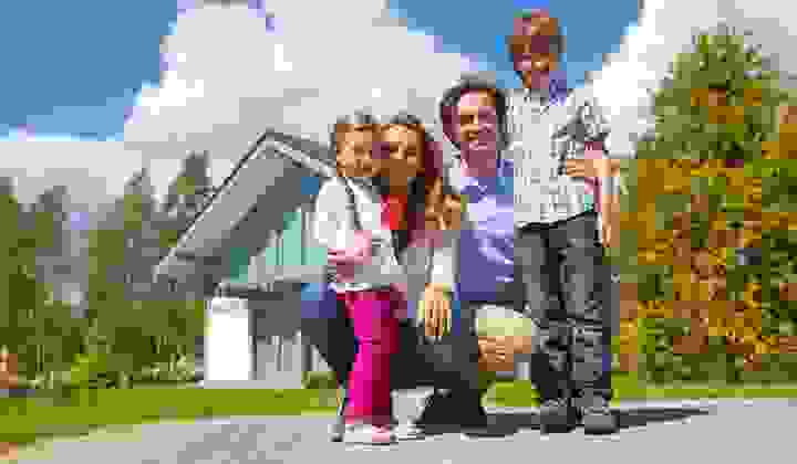 Smiling family group outside their new home on a sunny day