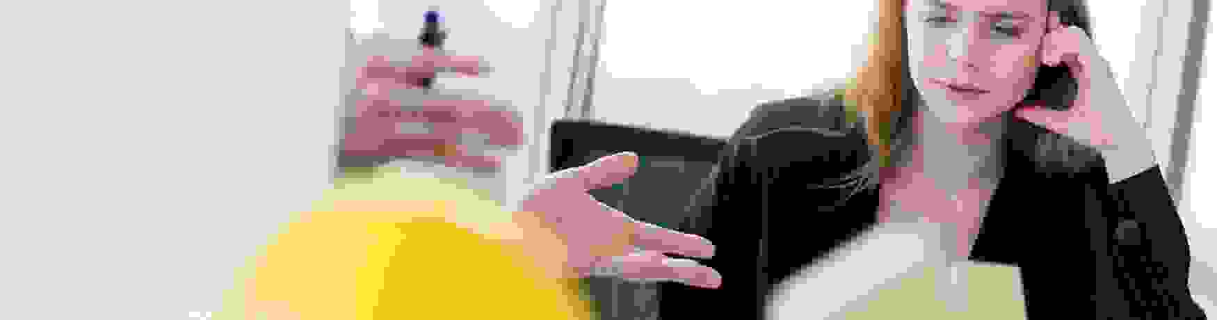 Business man discusses investment options with a woman in a suit in an office with a construction hat and house model blurred in foreground
