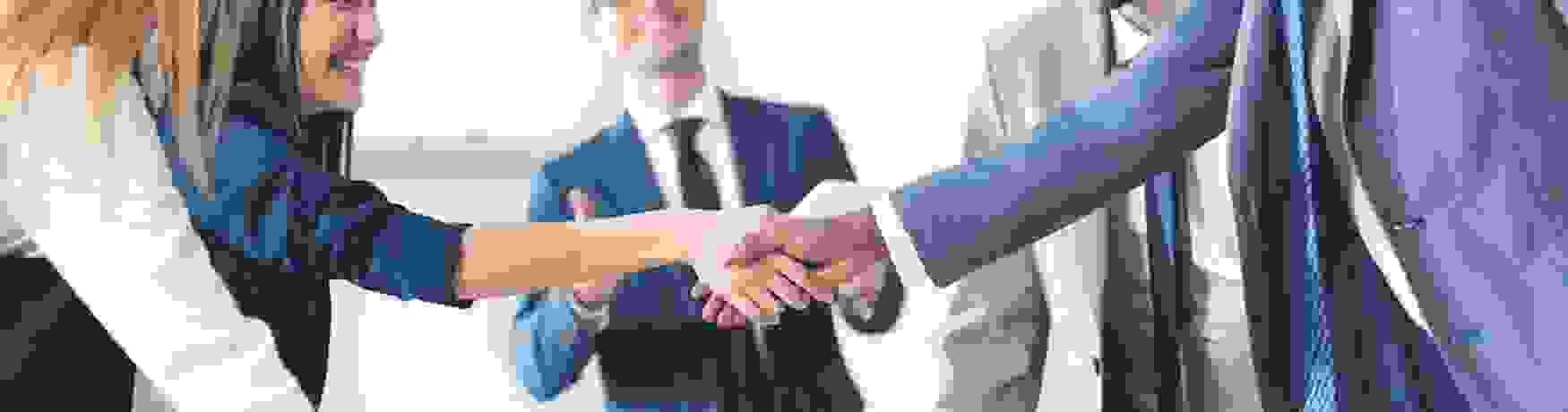 Group of business people in agreement shaking hands over a table with folders and water glasses