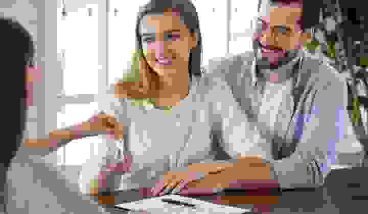 Young couple receiving keys from a rental agent.